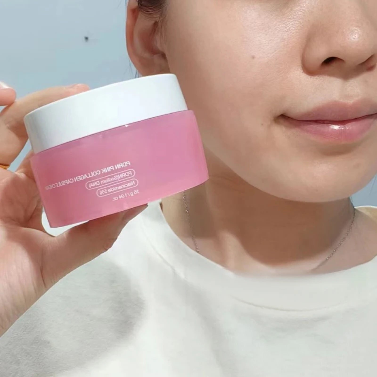 Modelo sosteniendo el pote de Medicube PDRN Pink Capsule Cream